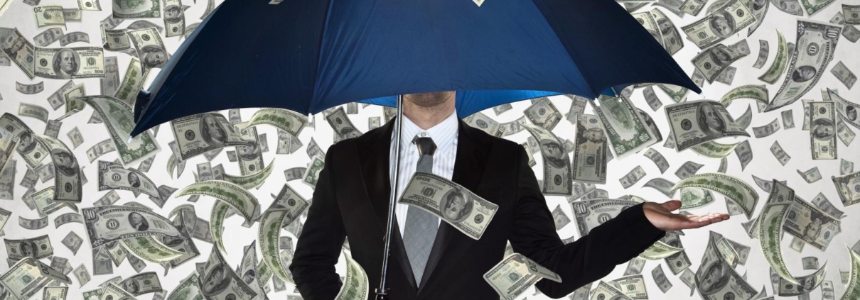 Egy férfi esernyővel áll a pénzesőben